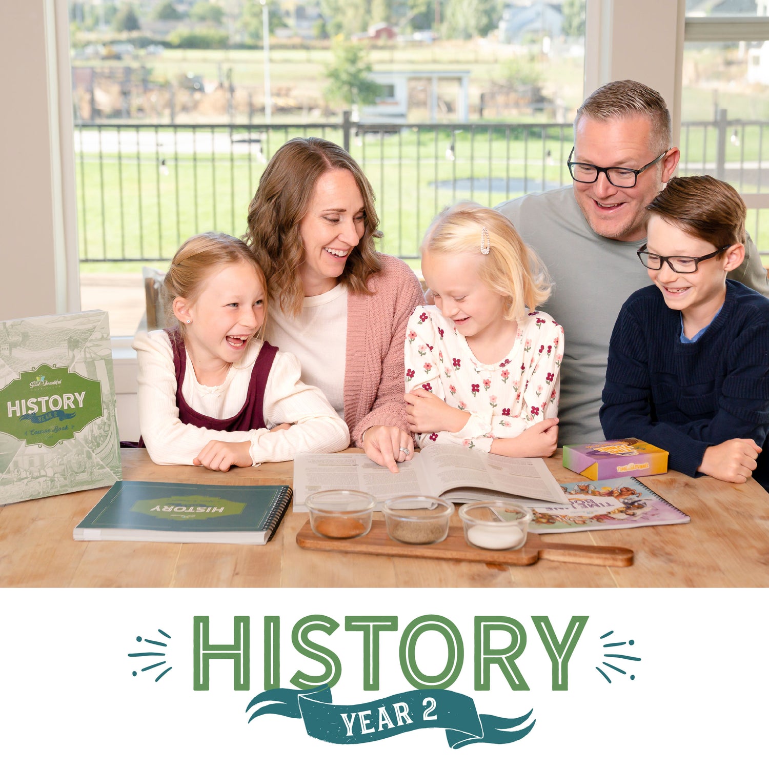 A family of five sitting at a table together with an open course book and other history course books set on the table | The Good and the Beautiful