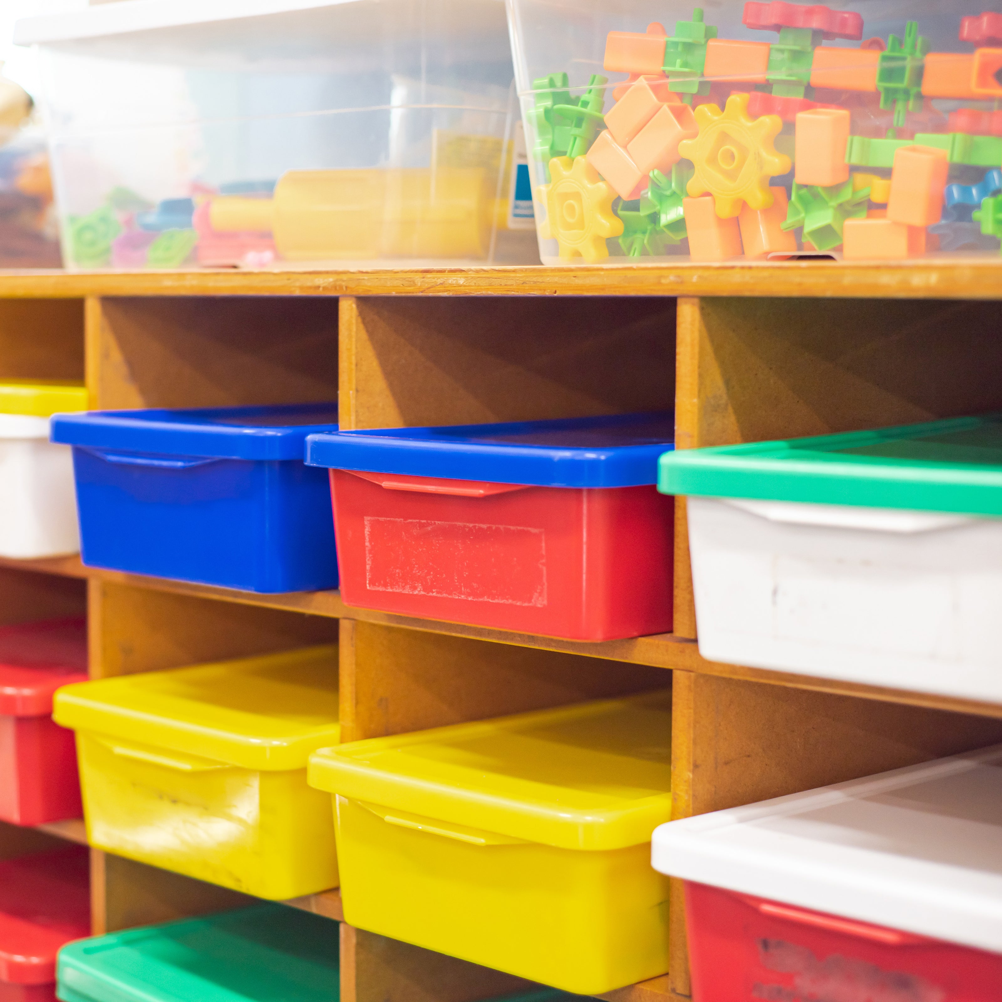 Colorful bins in cubbies with bins of toys above | The Good and the Beautiful