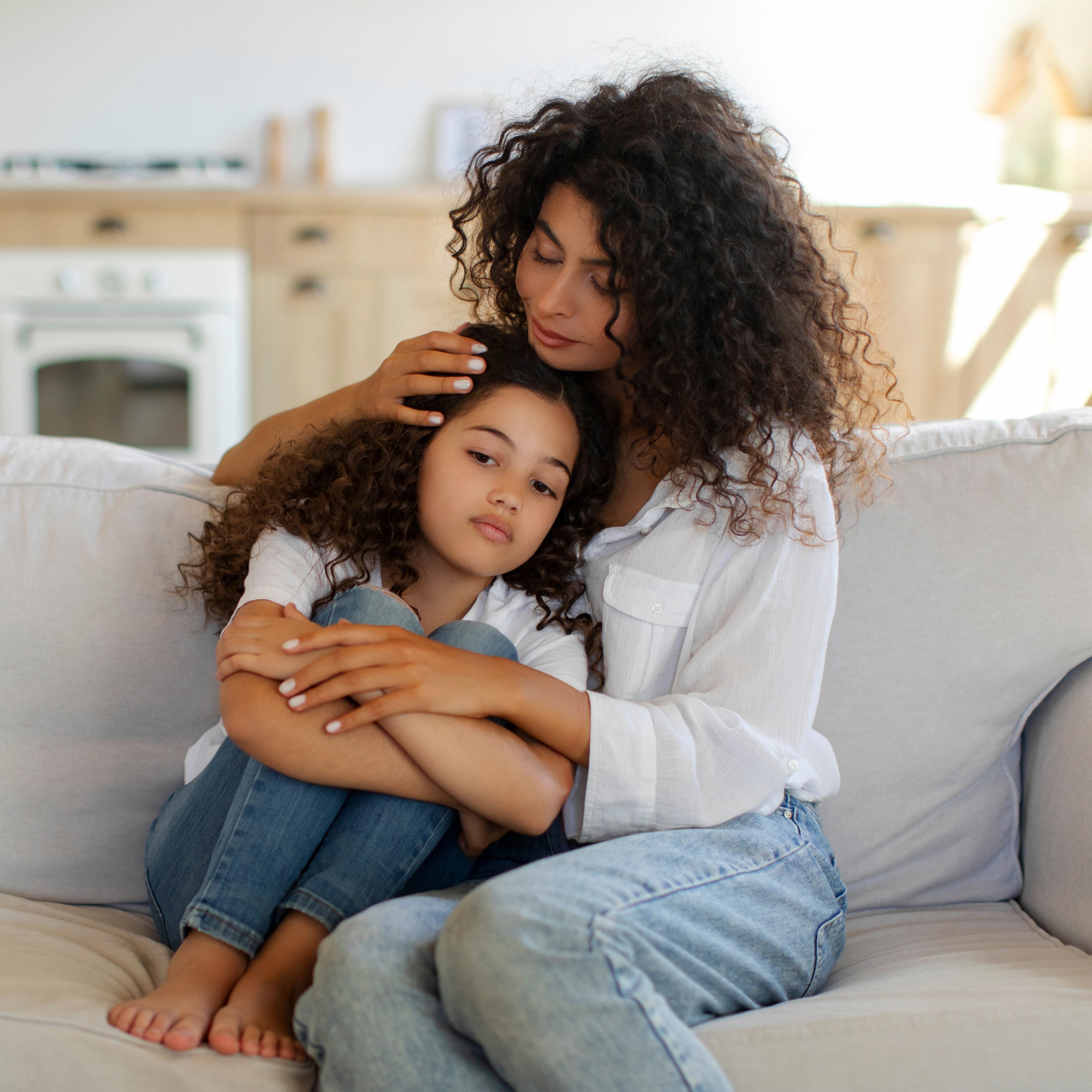 A mother cuddling with her school-aged daughter on the couch | The Good and the Beautiful