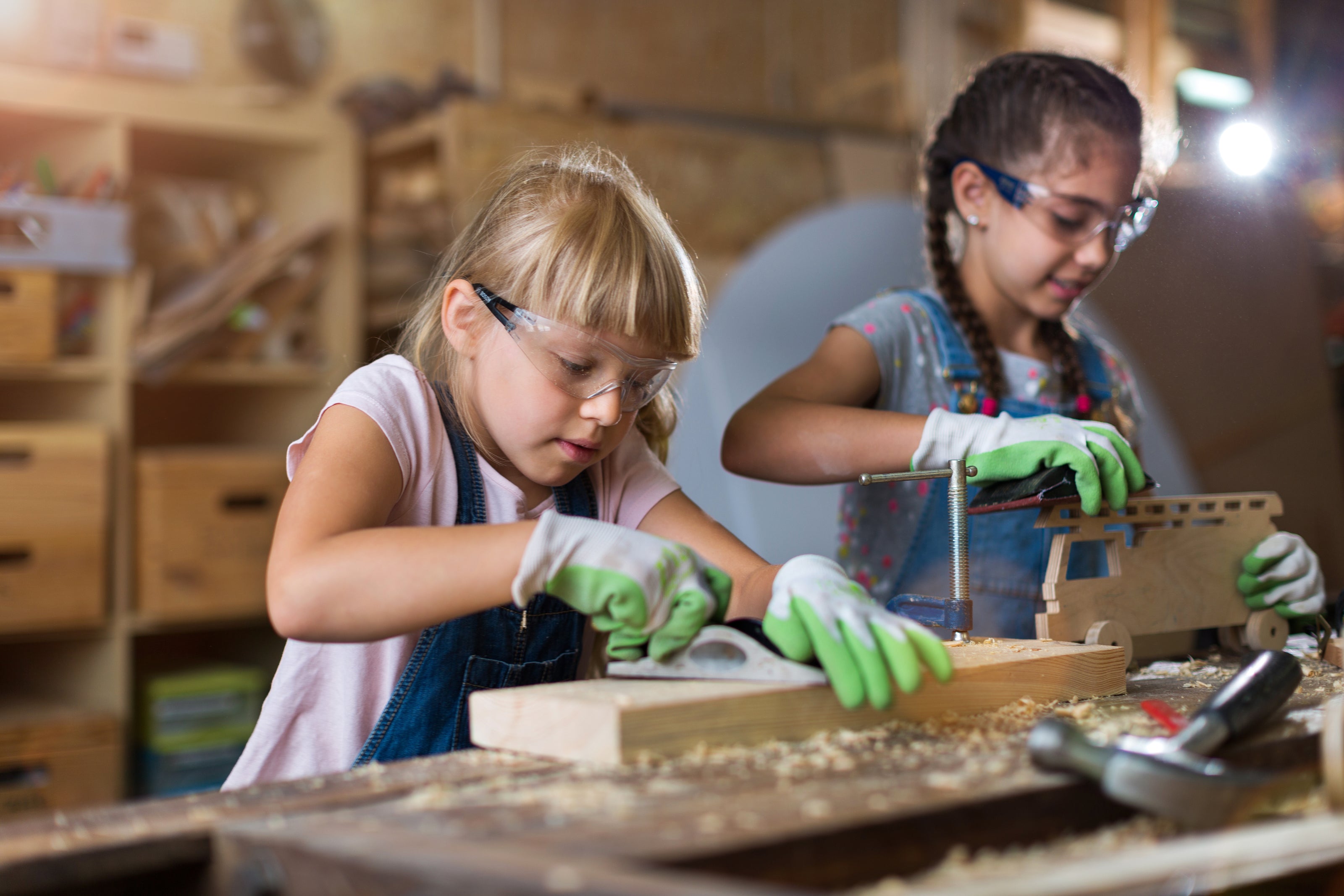 Two young girls working on a craft project in a workshop.