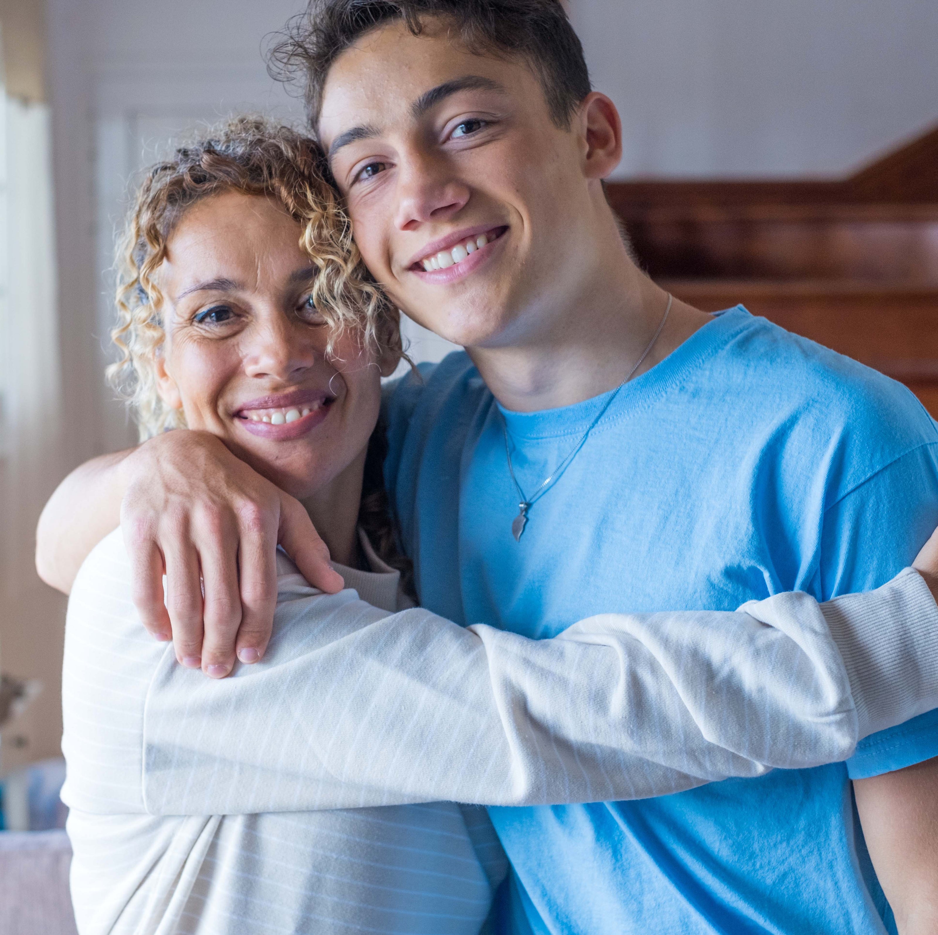 A mother hugging her son with his arm around her and their heads touching as they smile at the camera | The Good and the Beautiful