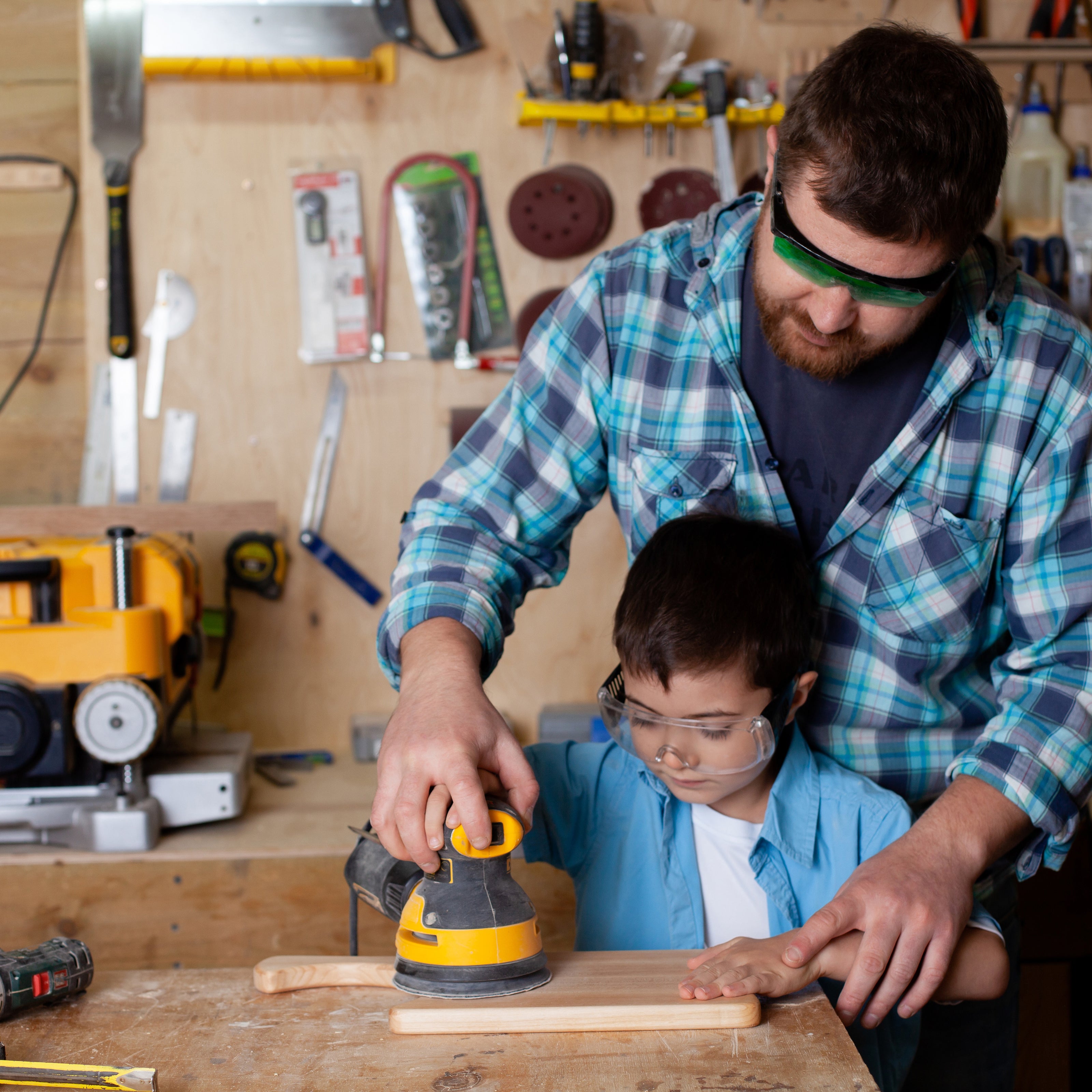 A father teaching his school-aged son how to sand wood | The Good and the Beautiful