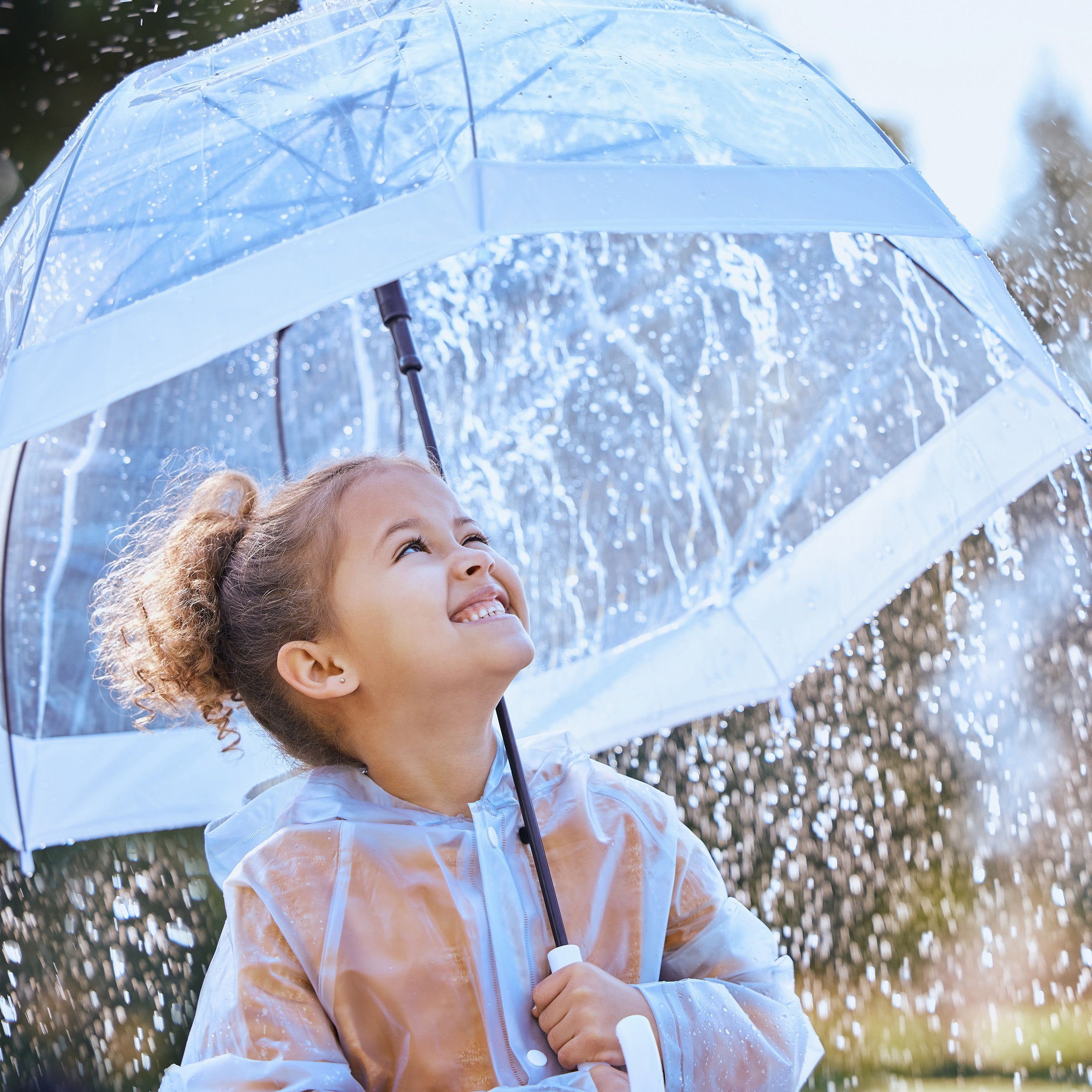 Young child under an umbrella, smiling, while it's raining
 | The Good and the Beautiful Blog