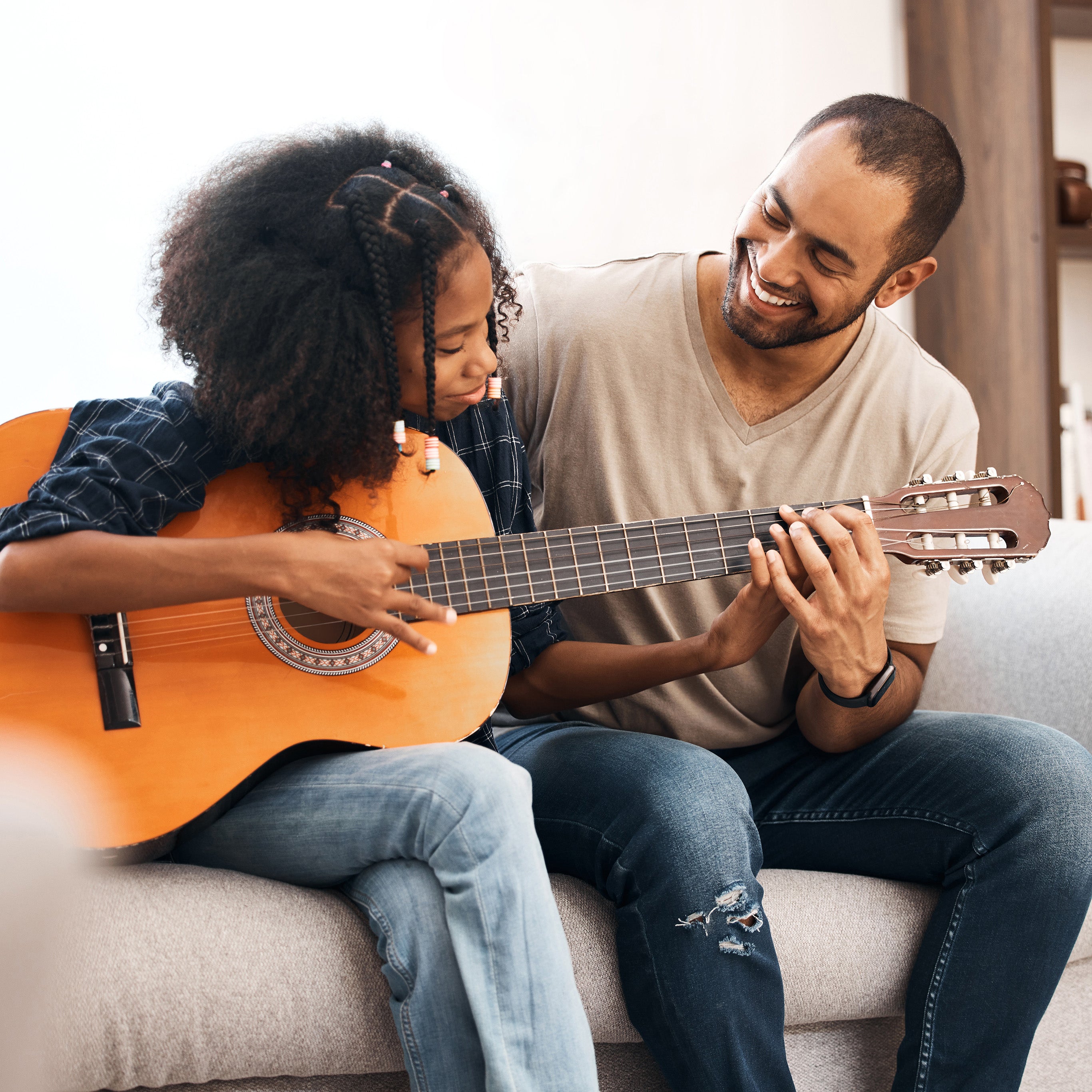 A father teaching his school-aged daughter how to play the acoustic guitar | The Good and the Beautiful