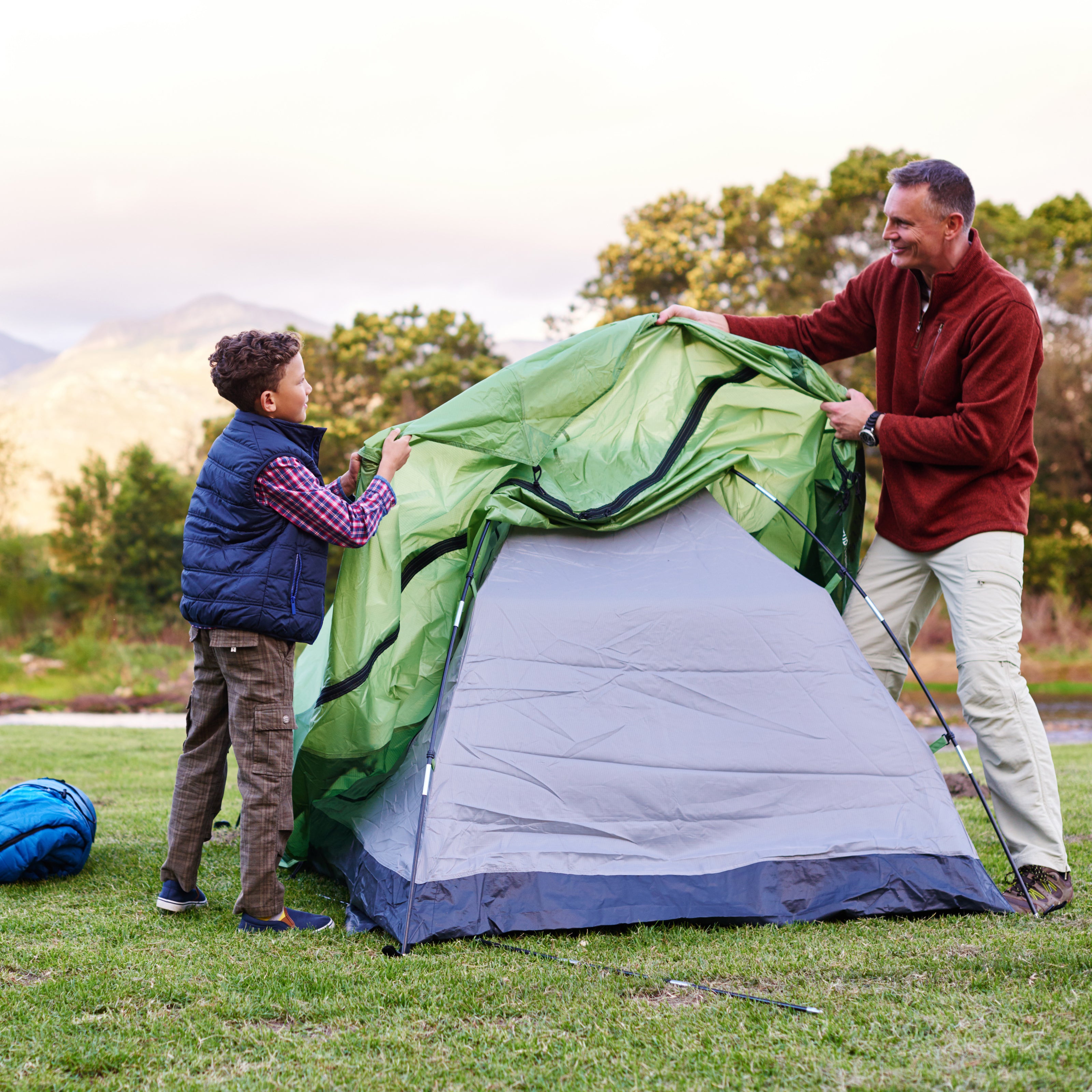 A father and son putting up a tent together | The Good and the Beautiful