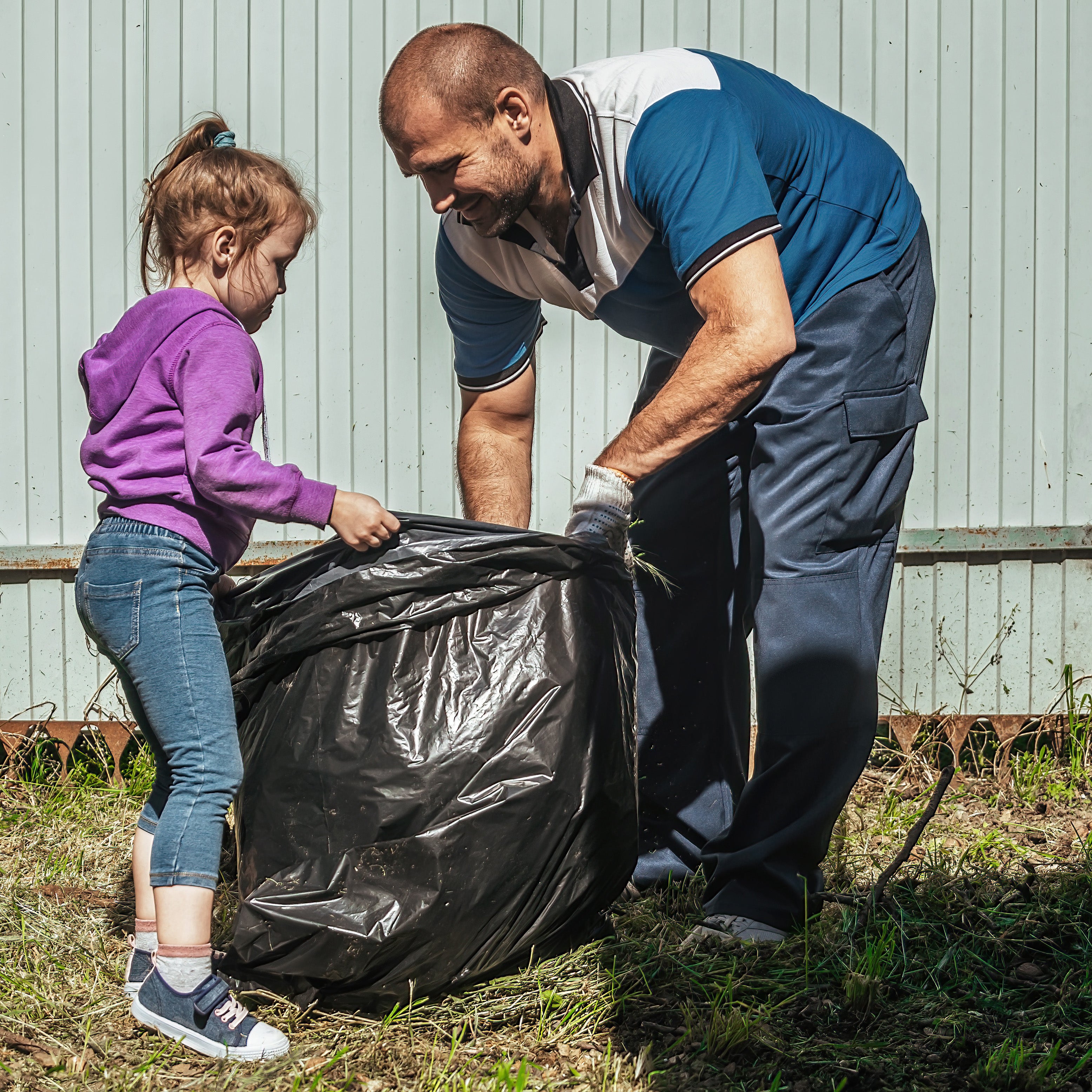 A school-aged girl helping her father pick up trash outside | The Good and the Beautiful