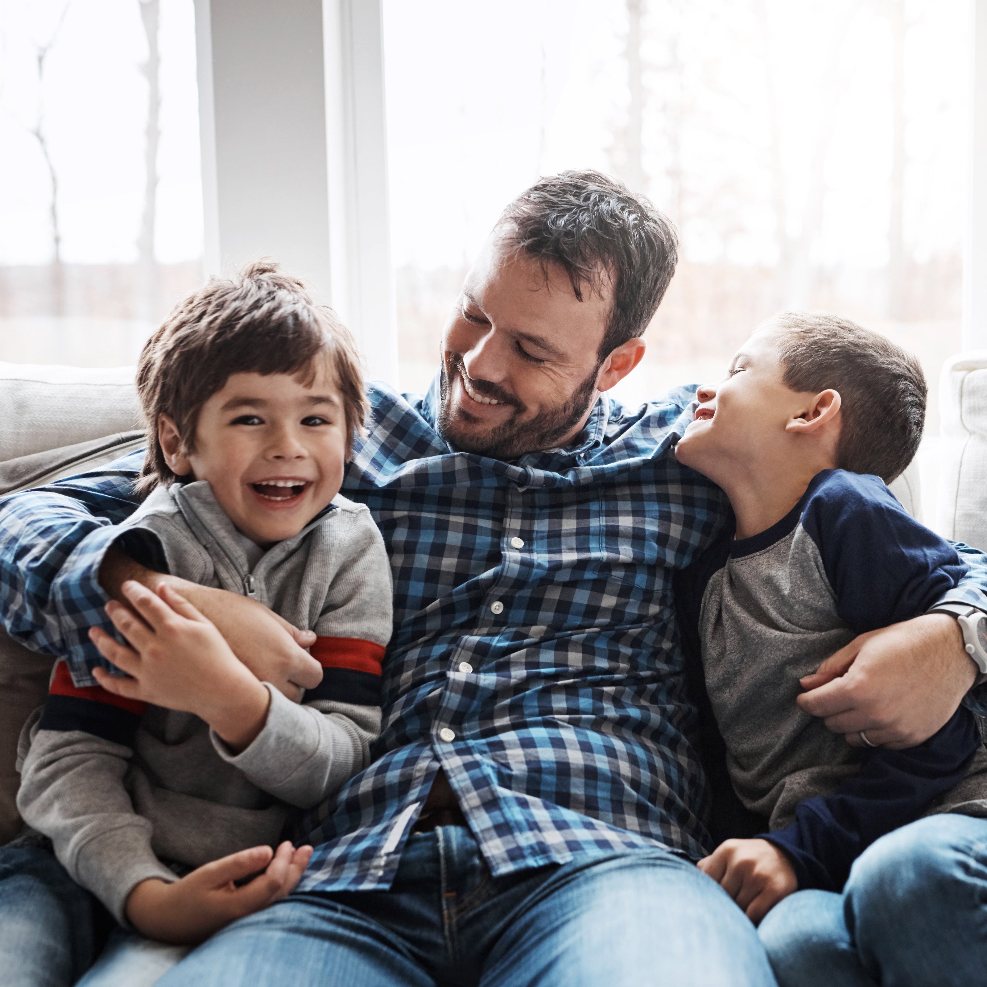 Father with two children sitting on a couch, smiling and laughing