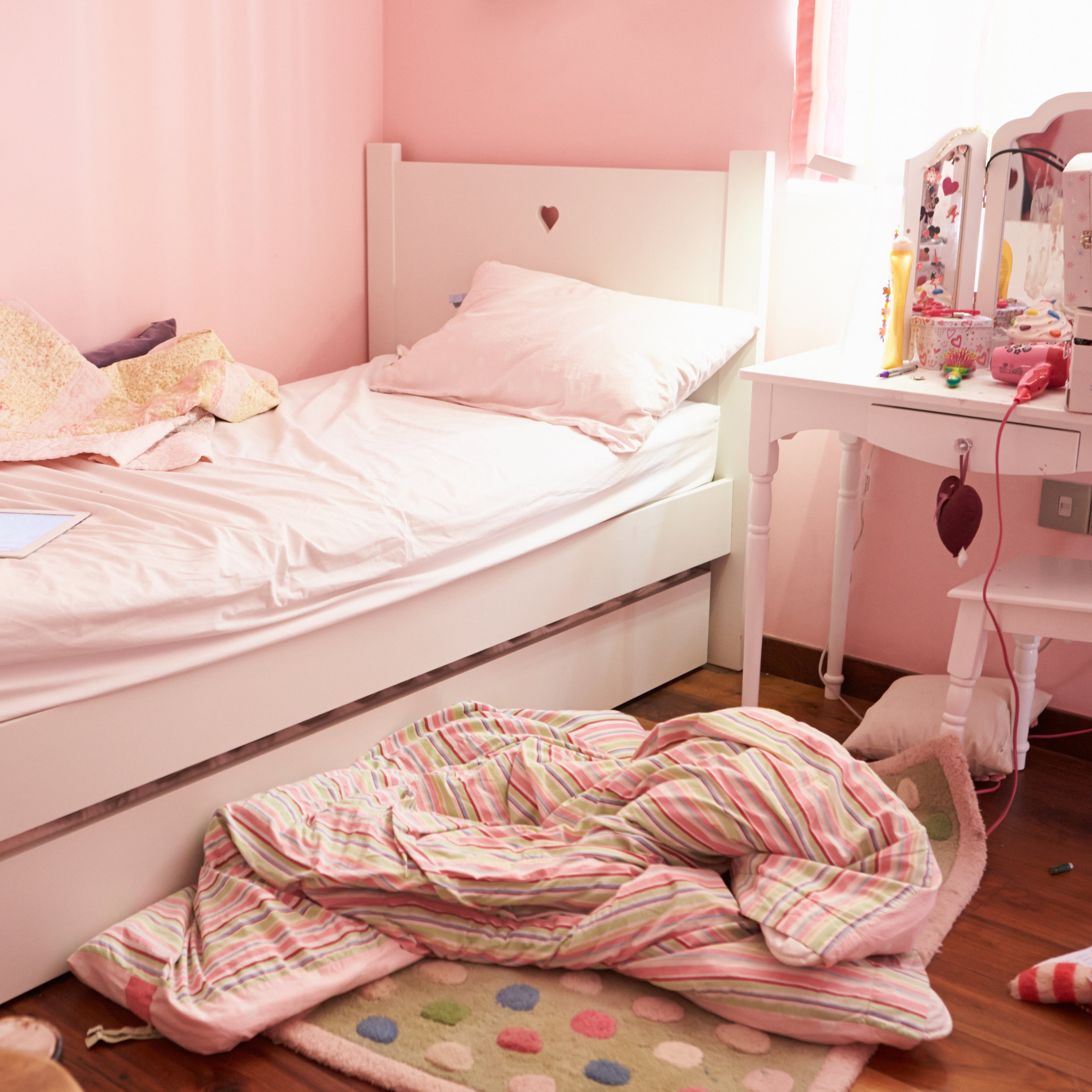 A child's pink room with an unmade bed and objects on the floor | The Good and the Beautiful