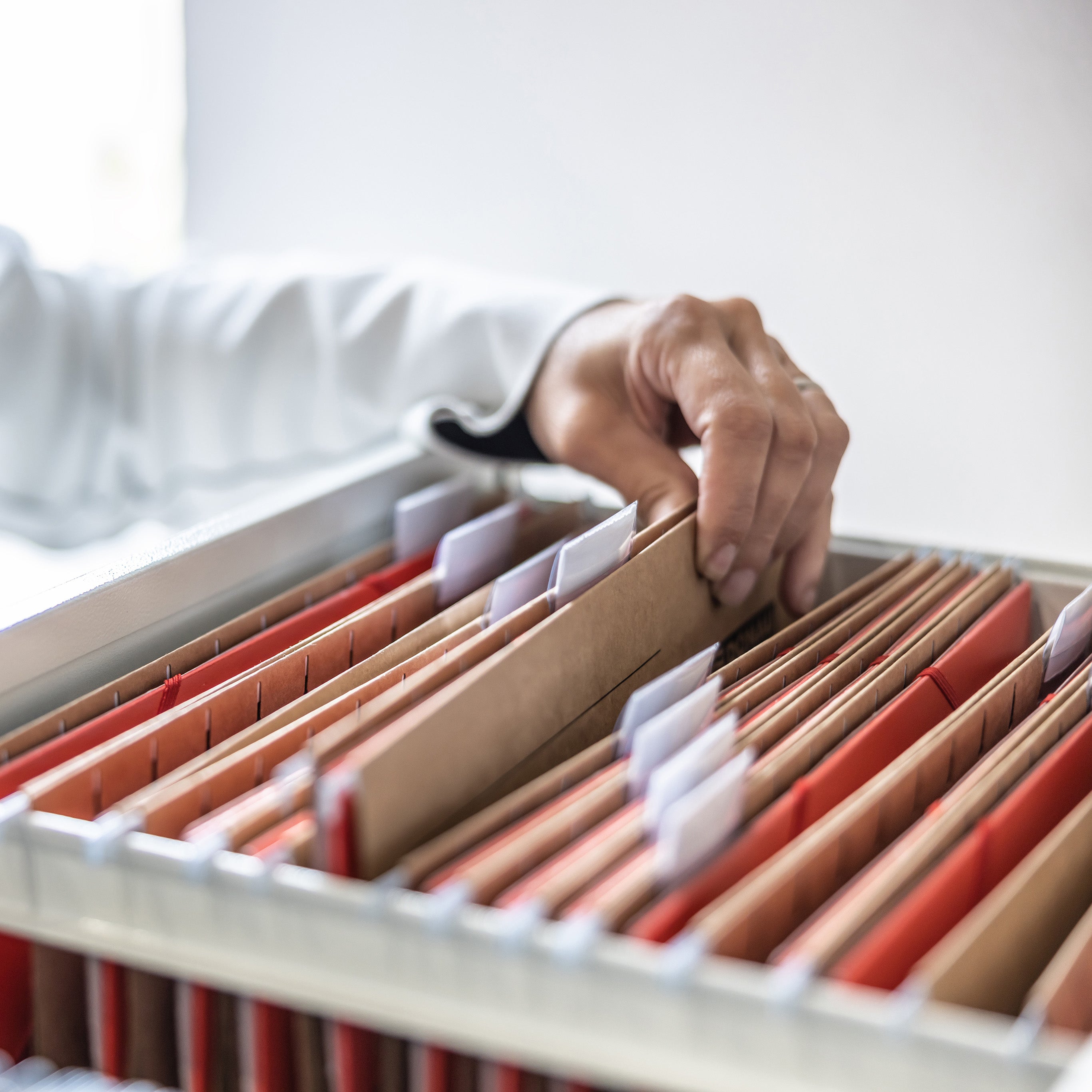 A hand pulling a brown file folder out of a filing drawer | The Good and the Beautiful