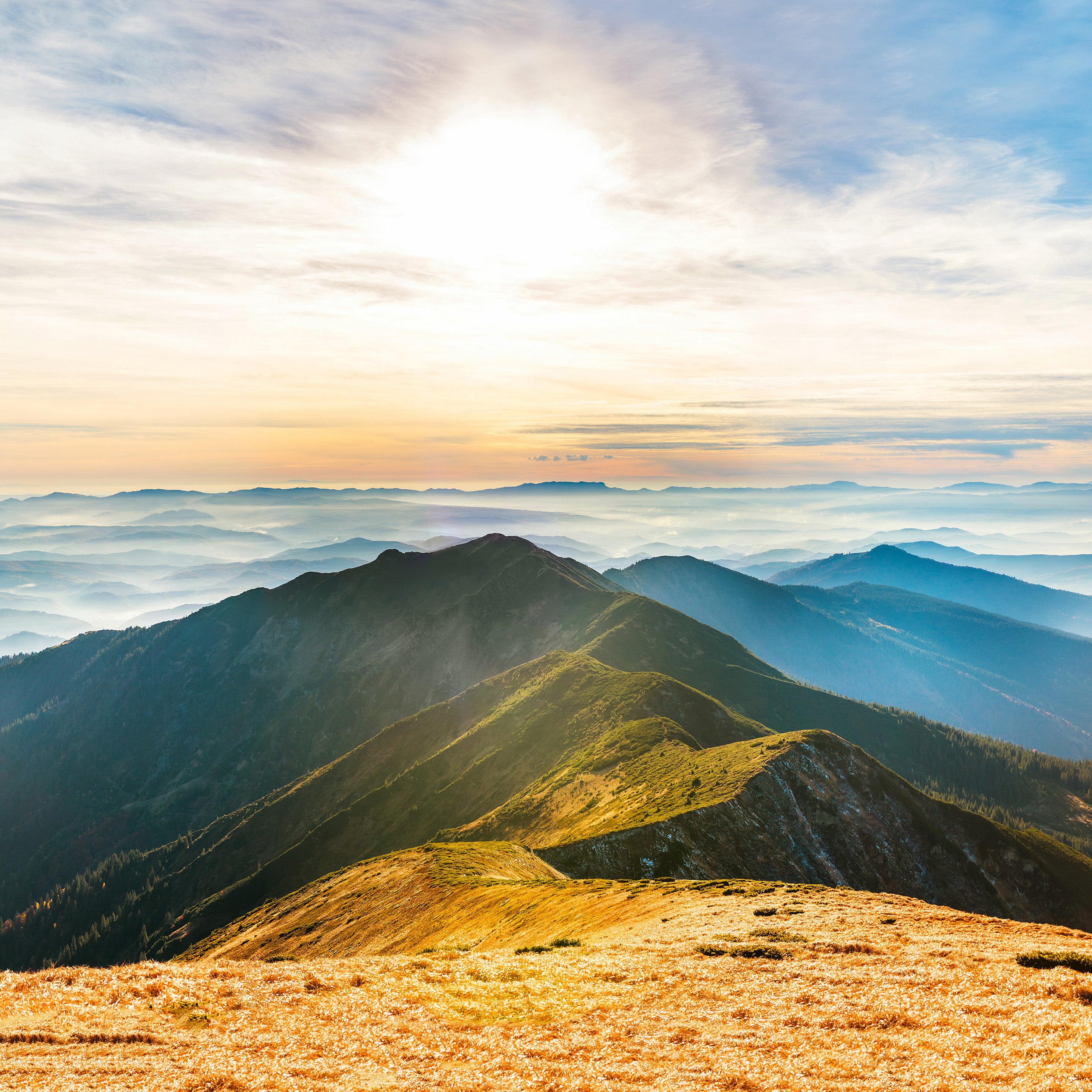 A photo of a sunny sky over the top of foggy mountains | The Good and the Beautiful