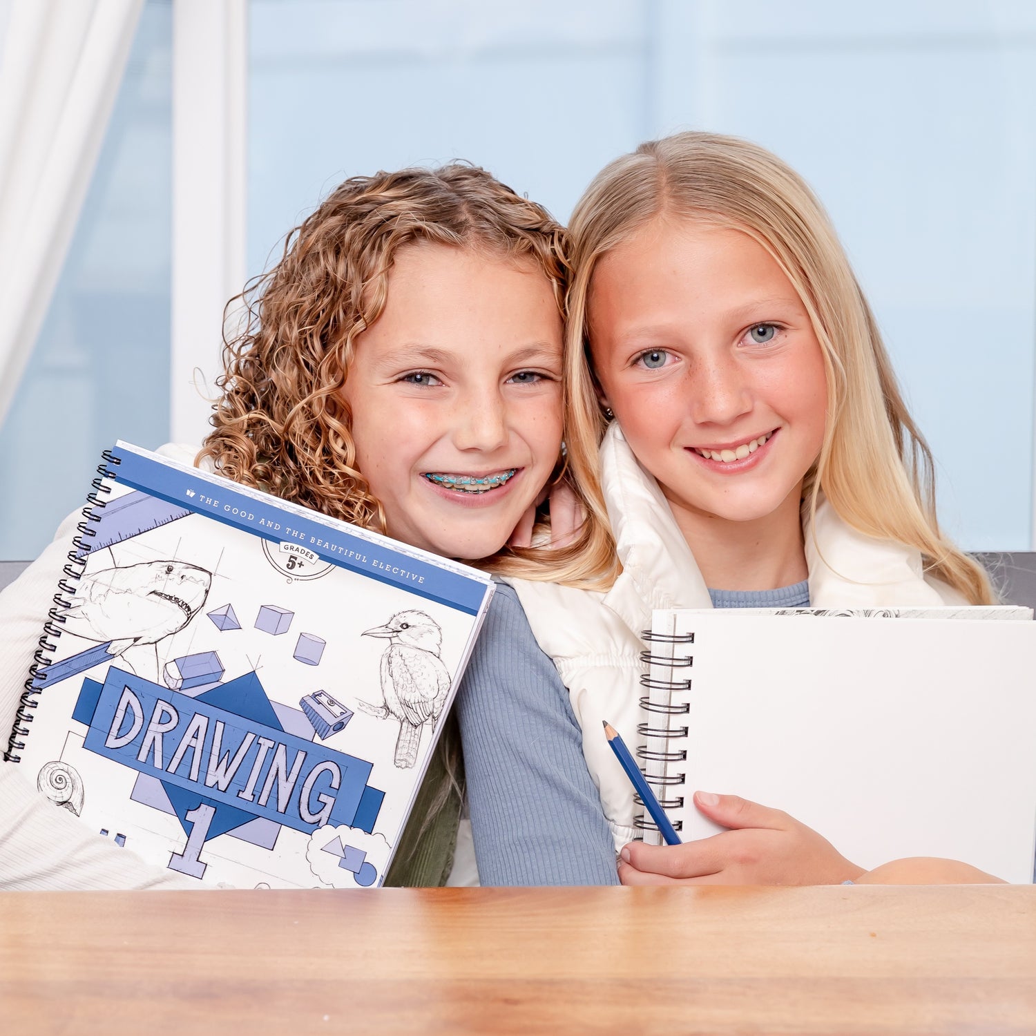 Two young girls sitting and holding the Drawing 1 Elective book | The Good and the Beautiful