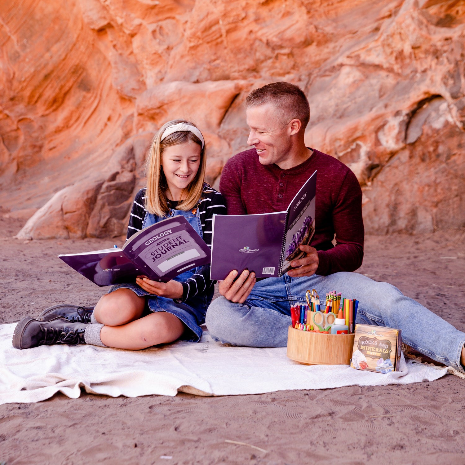A school-aged girl sitting with her father and holding a Geology student journal | The Good and the Beautiful