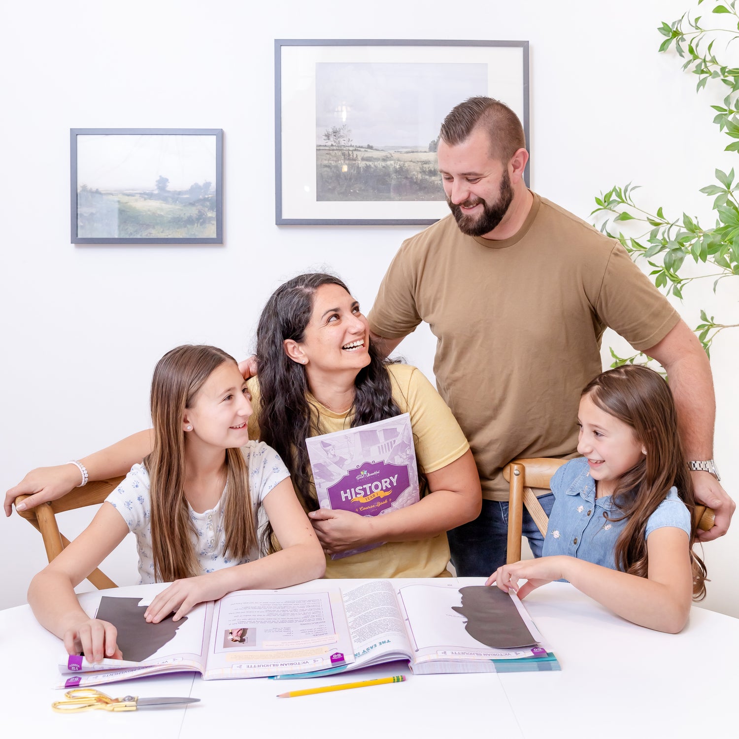 Two school-aged kids and their parents with History Year 1 course books on the table in front of them | The Good and the Beautiful