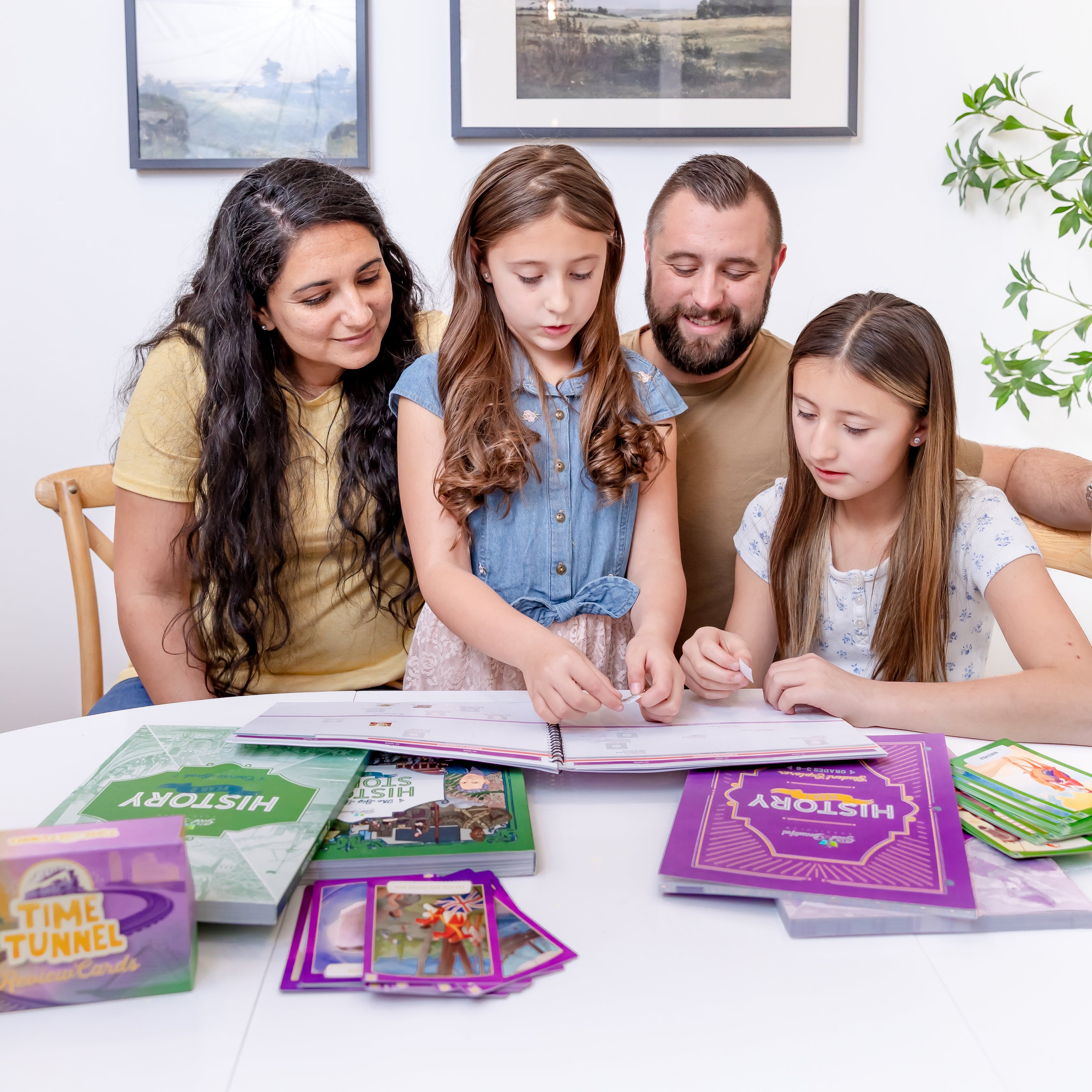 Two school-aged girls with their parents doing a history course activity | The Good and the Beautiful