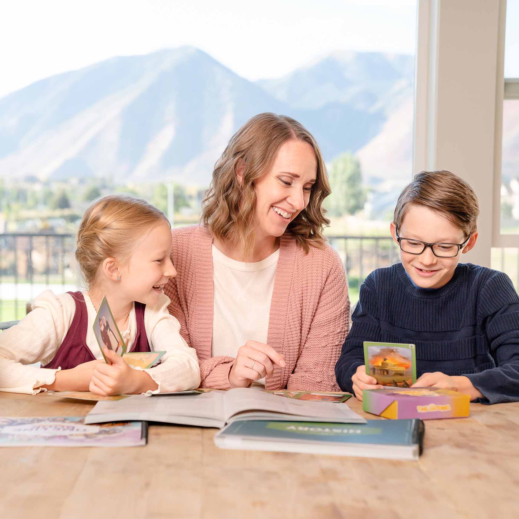 A mother and her two children sitting at a table working together on the history year 2 curriculum | The Good and the Beautiful