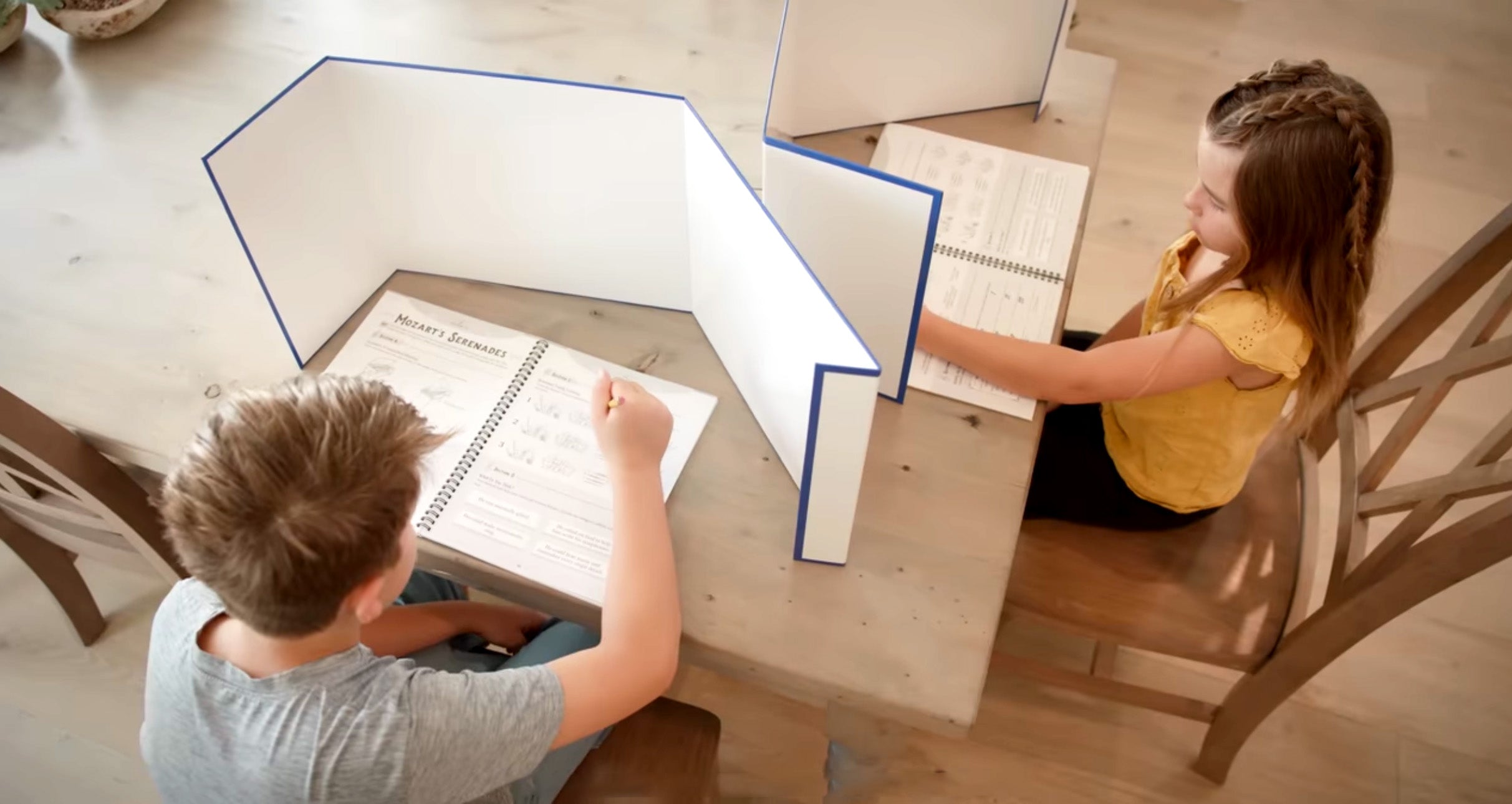 students doing school work with a trifold dry-erase board for privacy