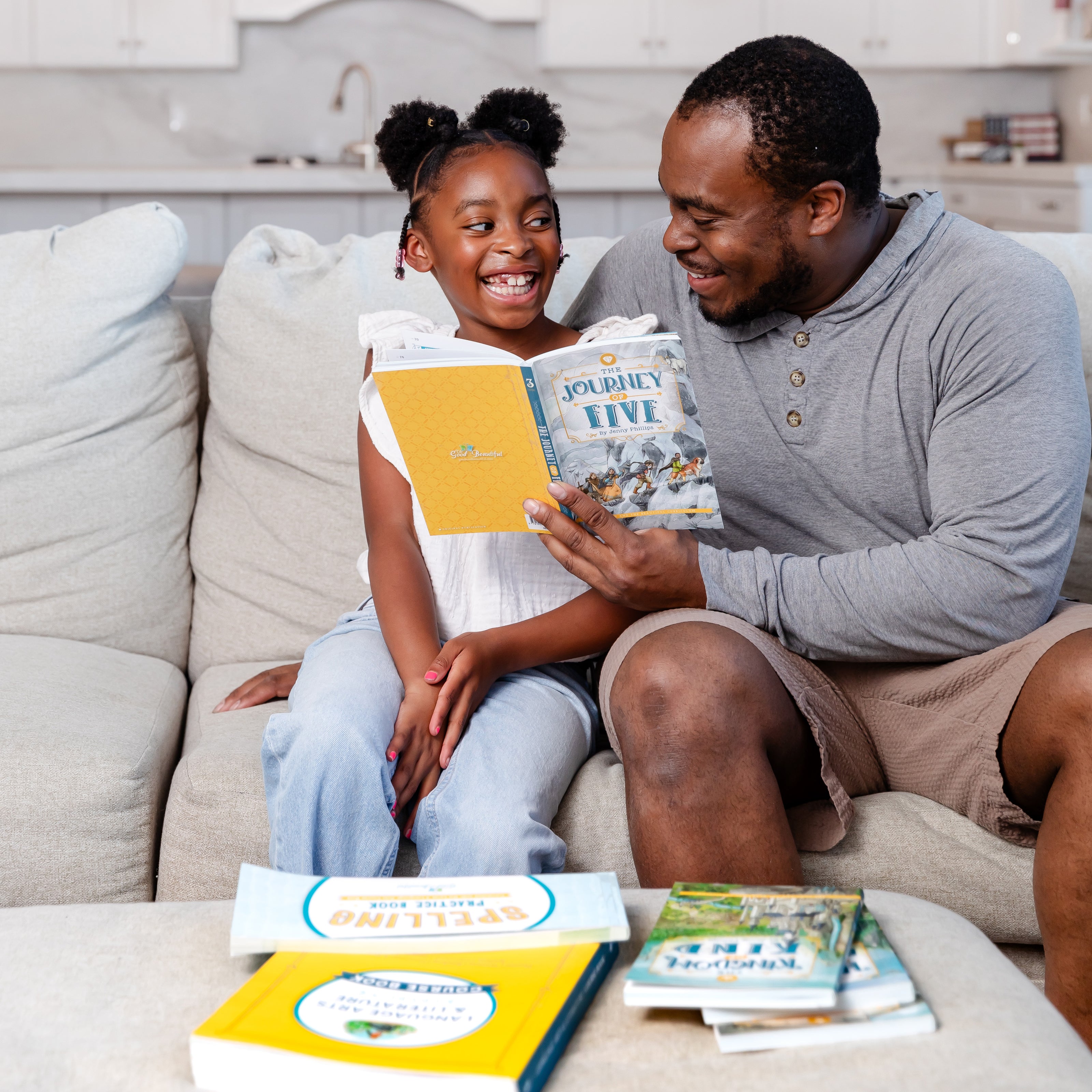 A school-aged girl sitting with her father reading the book "The Journey of Five" | The Good and the Beautiful