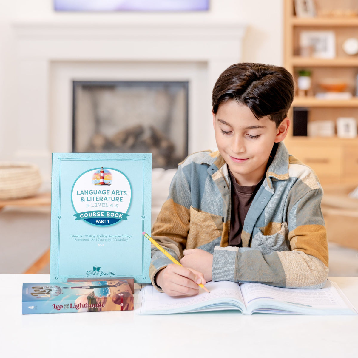 A school-aged boy sitting at a table writing in a level four language arts course book | The Good and the Beautiful