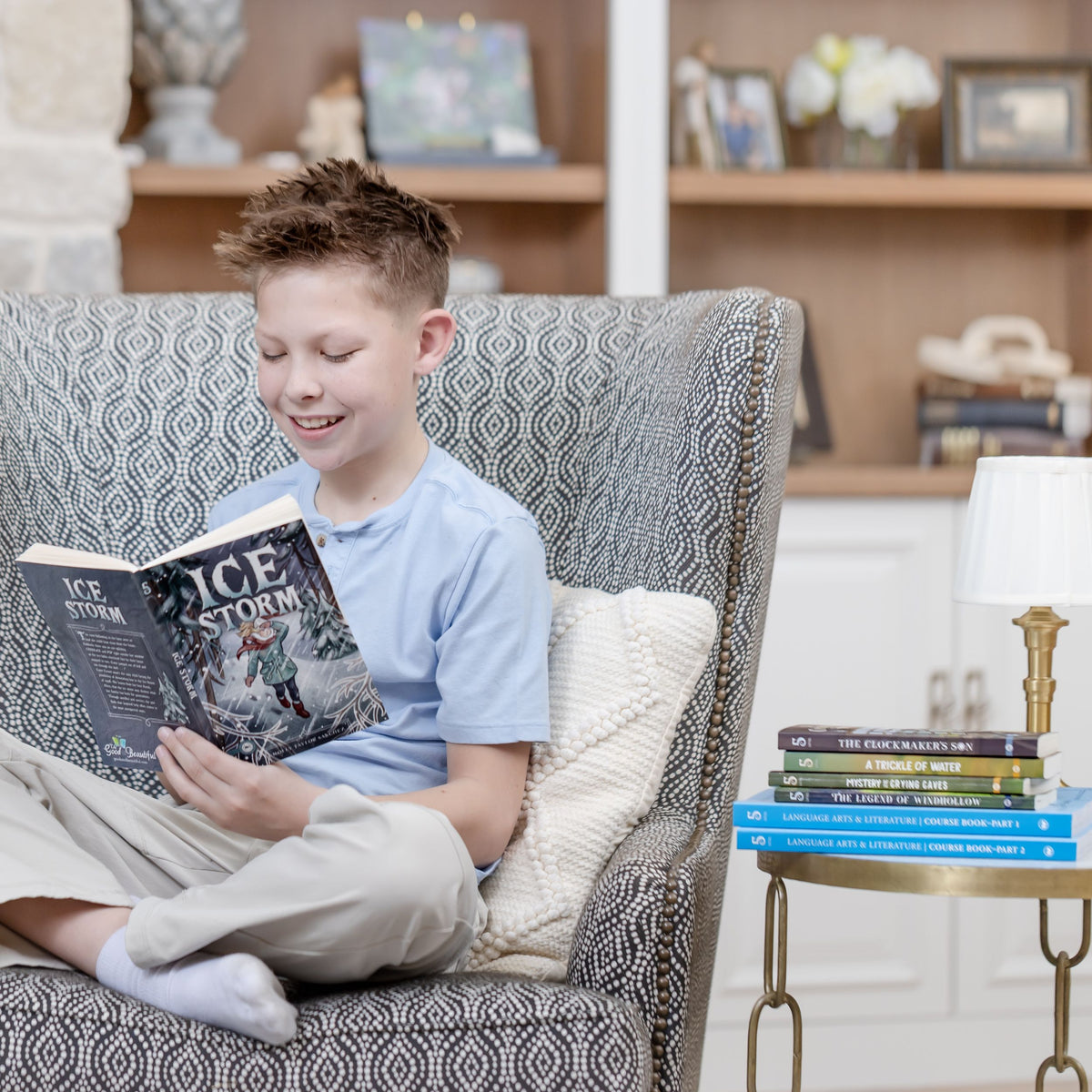 A school-aged boy sitting in a chair reading the book "Ice Storm" by Jenny Phillips | The Good and the Beautiful