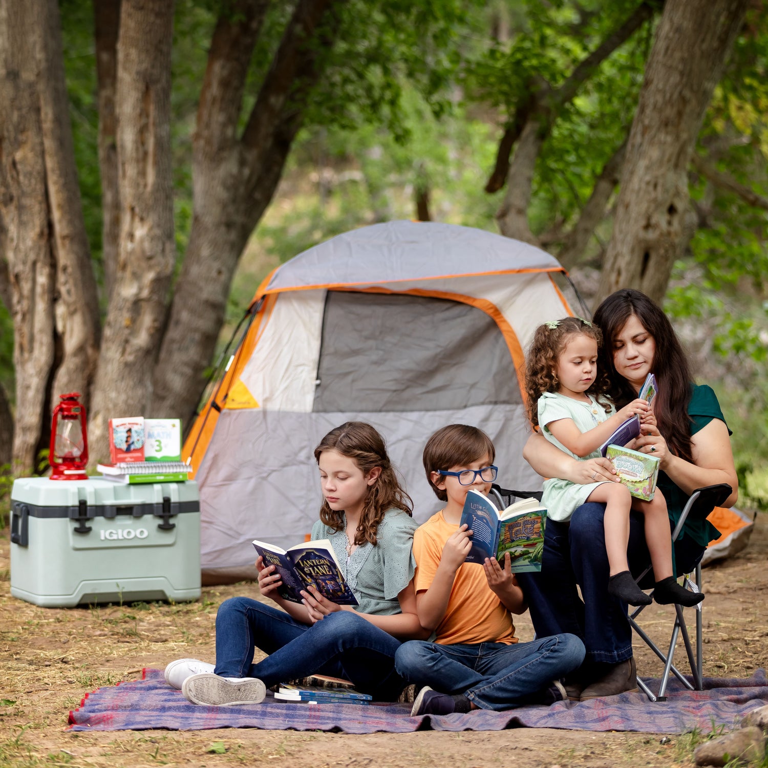 Family of four reading books from The Good and the Beautiful Bookshop in nature 