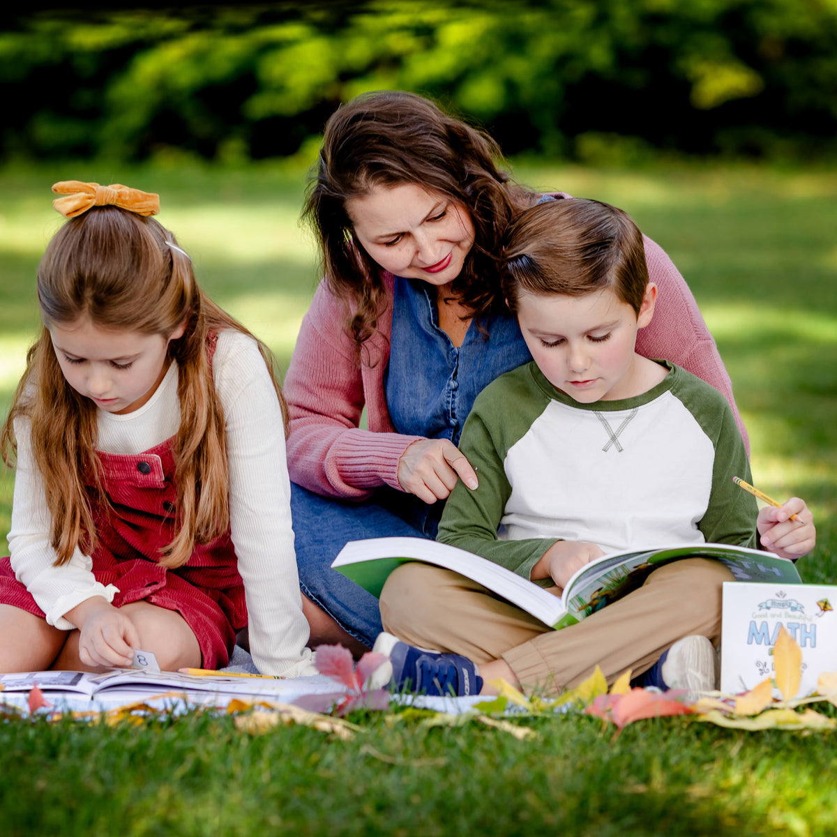 Two school-aged kids reading with their mom outside on a blanket | The Good and the Beautiful