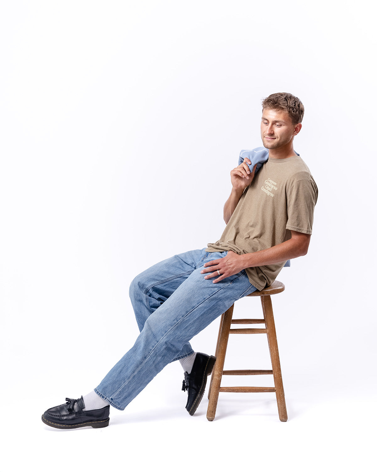 A man sitting and leaning on a stool with a brown t-shirt | The Good and the Beautiful