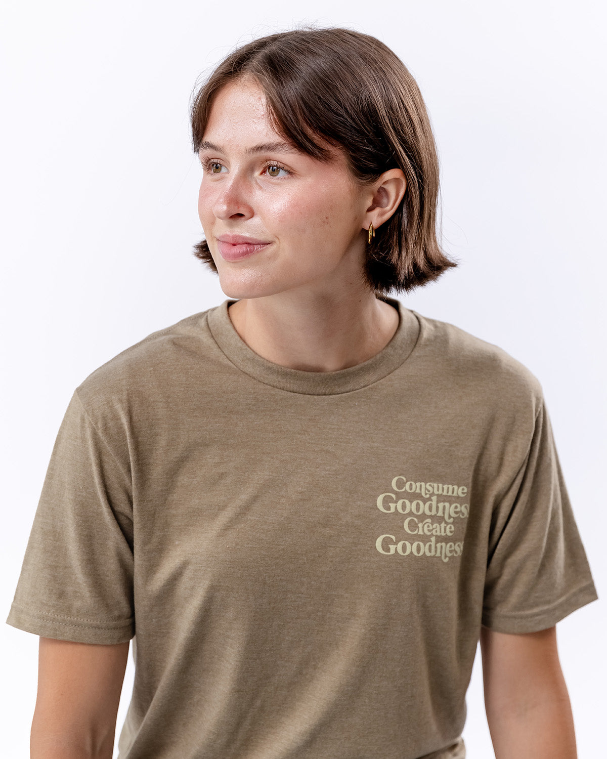 A woman posing with a brown t-shirt that says "Consumer Goodness Create Goodness" | The Good and the Beautiful