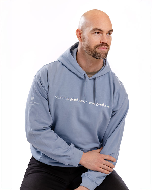 A man posing in a blue hoodie that says "Consume Goodness, Create Goodness" | The Good and the Beautiful