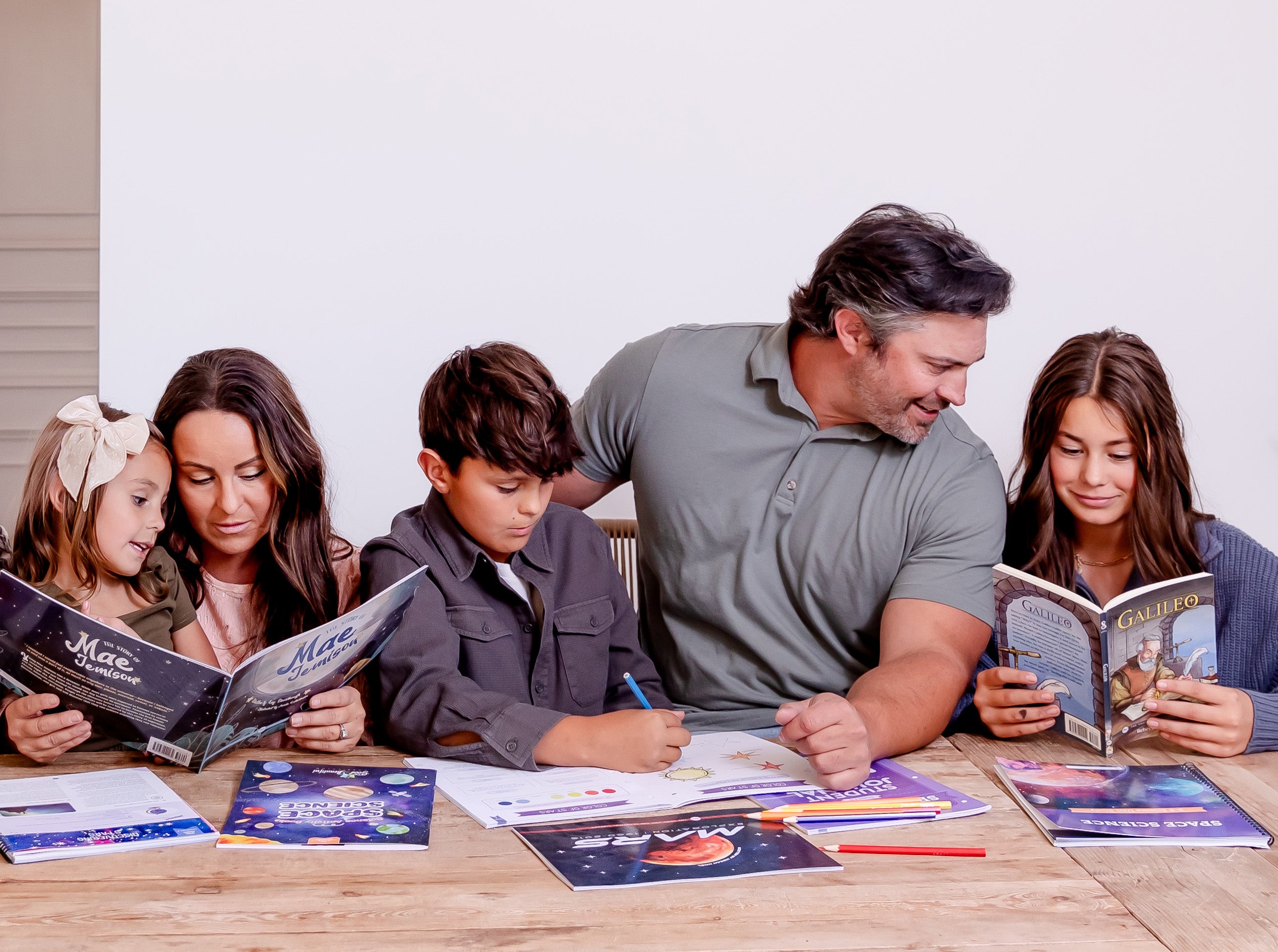 Three school-aged kids working on Space Science with their parents | The Good and the Beautiful