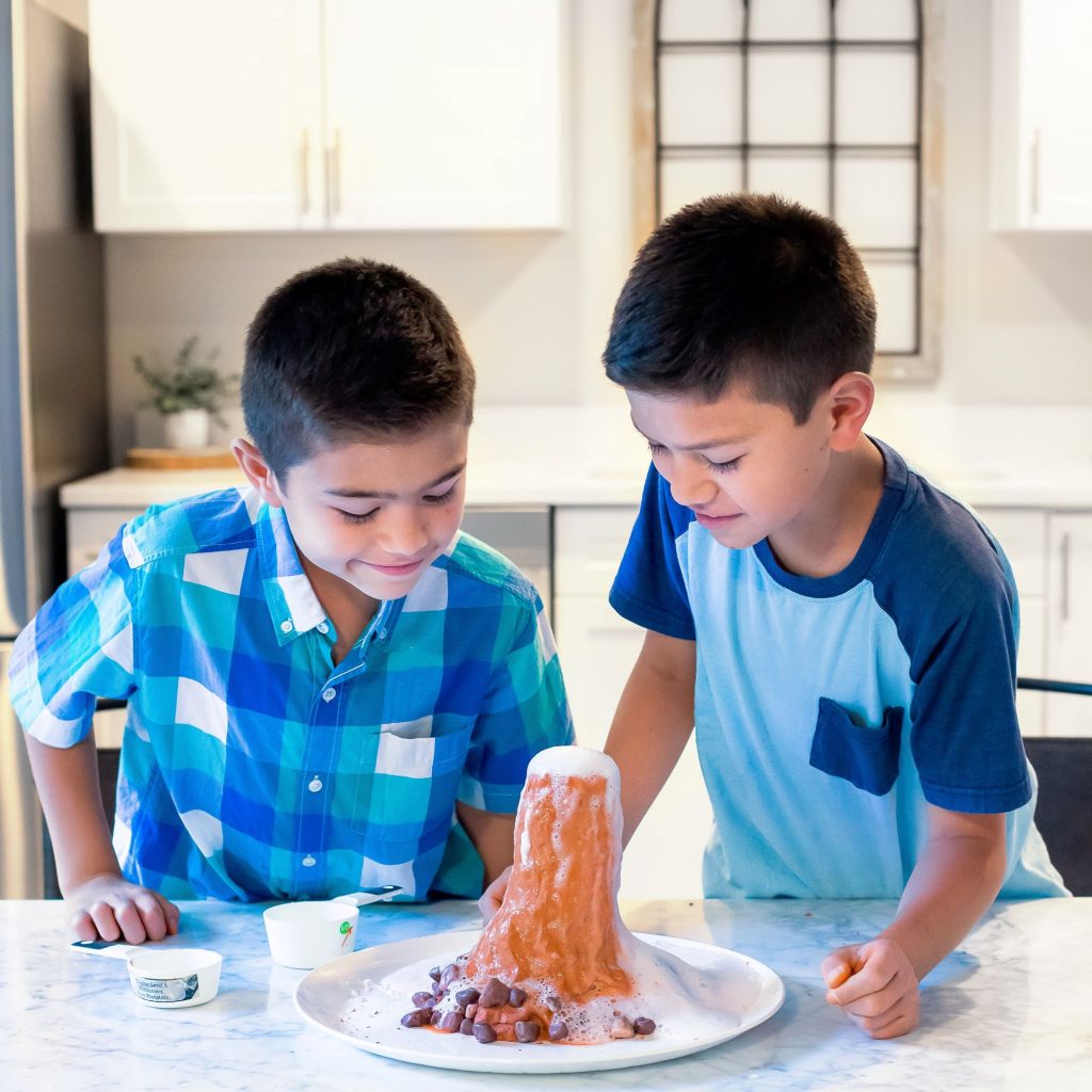 Photograph of two boys watching homemade volcano