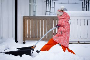 Young Girl shoveling snow by her house