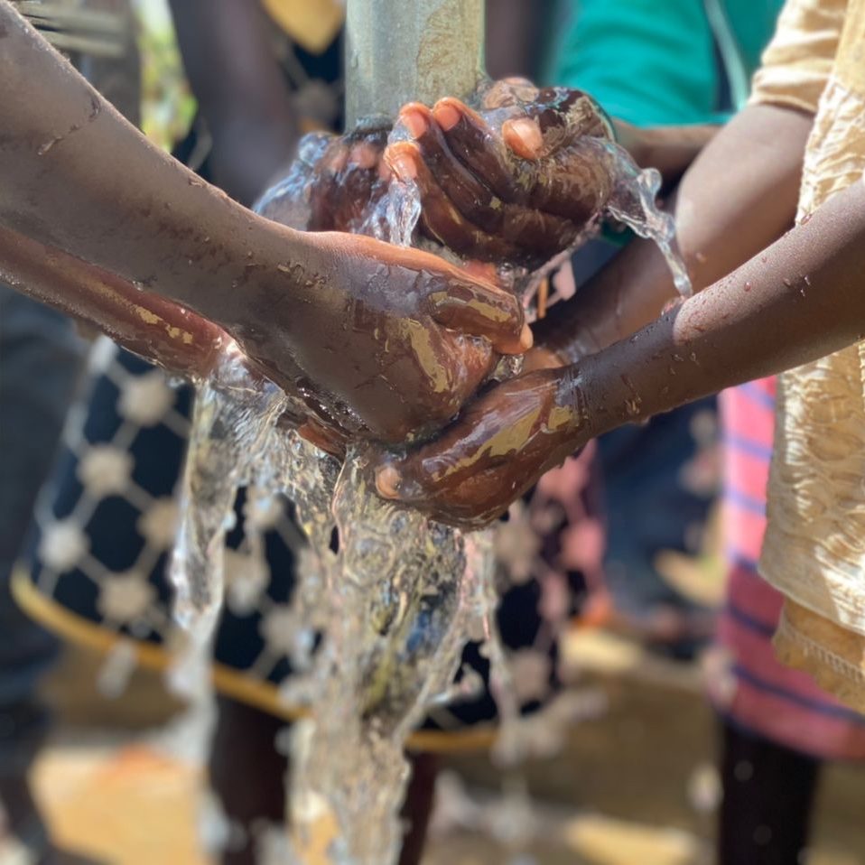 Photograph of hands in clean water from a humanitarian well dug in Africa