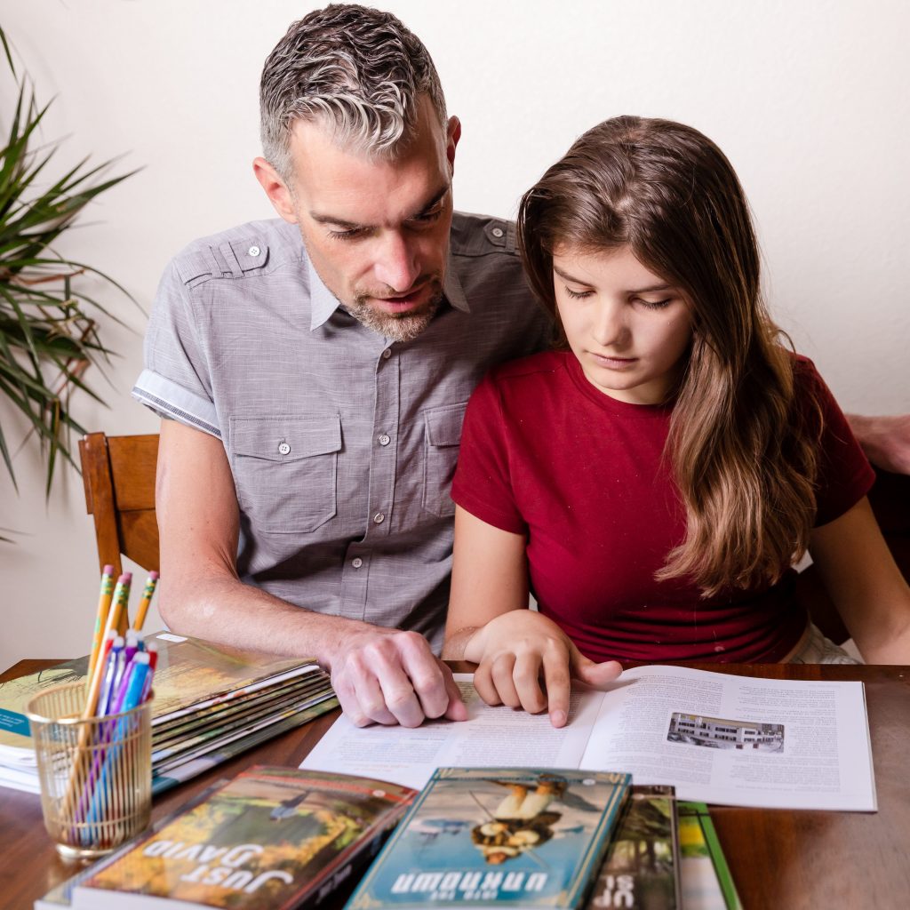 Photograph of Dad and Daughter Working on Homeschool High School Language Arts Curriculum by The Good and the Beautiful