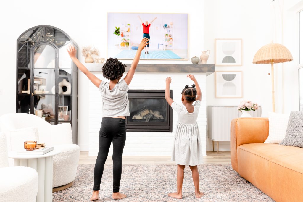 Photograph of two kids doing the kids exercise videos with arms up
